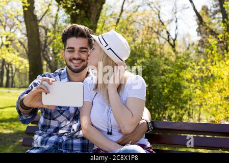 Closeup shot of a young attractive couple taking a happy selfie in a park Stock Photo