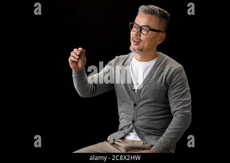 Sitting in a chair, a senior designer with a pencil Stock Photo