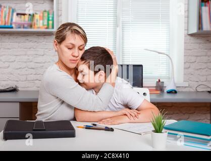 Mother helping her son making school homework at home Stock Photo