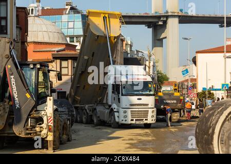 Road construction site in Ortakoy, Istanbul. Dump truck with open dumper, excavator and several road construction workers working in daytime. Stock Photo