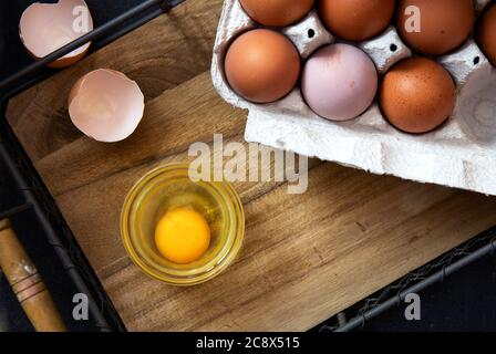 Bowl of raw egg and egg shell on a wooden tray. Organic food. Stock Photo