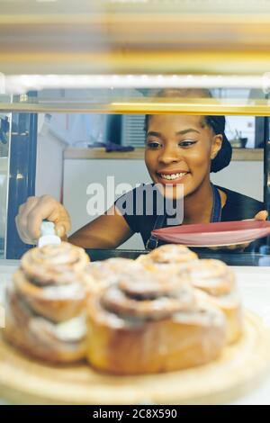 https://l450v.alamy.com/450v/2c8x590/happy-pretty-smiling-black-waitress-taking-cinnamon-bun-from-showcase-to-serve-for-customers-2c8x590.jpg