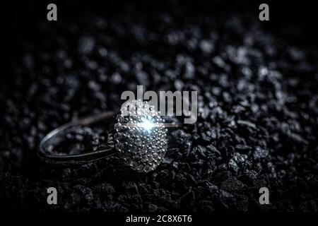Silver ring with stones on black coal background Stock Photo