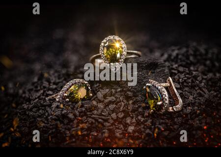 Jewelry ring and earrings witht big yellow gems on black coal background Stock Photo