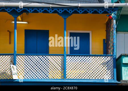 Pretty colourful veranda on a house with blue and white railings and yellow walls in Roseau, Dominica island, The Caribbean Stock Photo
