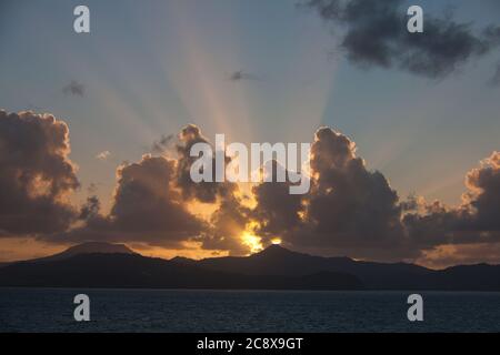 Dramatic sunrise over the west coast of St Lucia in The Caribbean, with sun's rays causing sunbeams over the hills in silhouette Stock Photo
