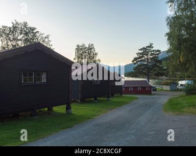 View of Classical Norwegian Camping site Bravoll with traditional wooden cottages cabins at Kinsarvik by the Sorfjorden branch of Hardanger Fjord in Stock Photo