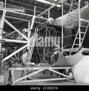 1950s, historical, two engineers at an aviation manufacturer in a large hanger checking an external steel panel for the fuselage or main body of a large aircraft being constructed, Belfast, N. Ireland, UK. Stock Photo