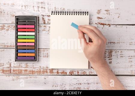 Colored wax crayons  and open sketchbook on wooden background. Hand drawing on  sketchbook. Flat lay, top view, copy space. Stock Photo