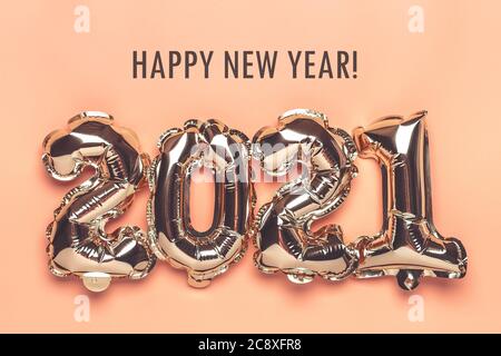 Gold foil balloons numeral 2021 isolated on beige background Flat lay creative composition Top view Happy New year 2021, Merry Christmas concept Stock Photo