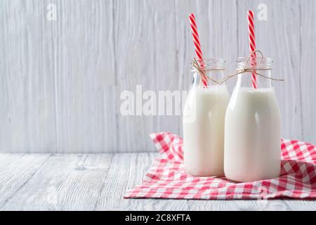 Bottles of milk with red straws and checkered towel on wooden background Stock Photo