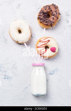 Donuts on a drinking straws with bottle of milk on a stone table, top view Stock Photo