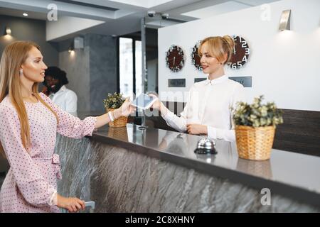 Young attractive woman with packed suitcase standing in hotel lobby Stock Photo