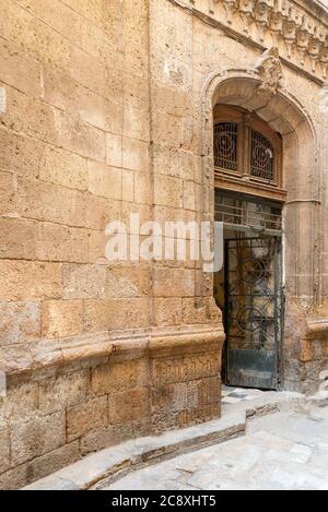 Angled view of grunge door with ferforge wrought iron grill on grunge stone bricks wall in abandoned district Stock Photo