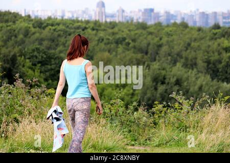 Girl with smartphone walking in a park on city background. Summer leisure and hiking Stock Photo