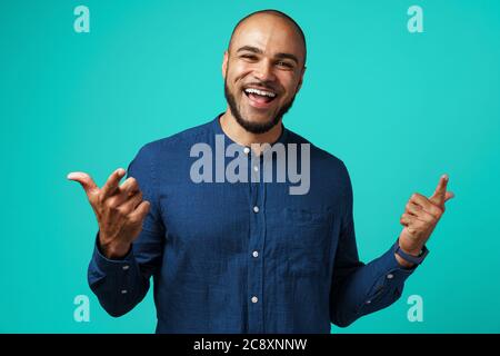 Joyful dark-skinned man laughing against turquoise background Stock Photo