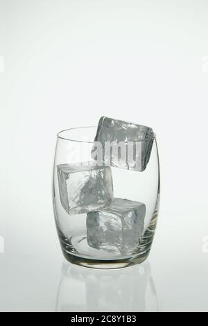 Photograph of three fake ice cubes in a glass tumbler on a light background. Stock Photo
