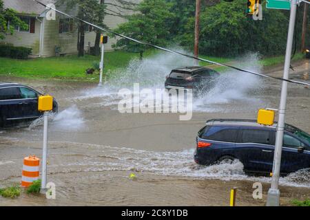 Water splashes street flooded heavy rain on residential city street during pavement car Stock Photo
