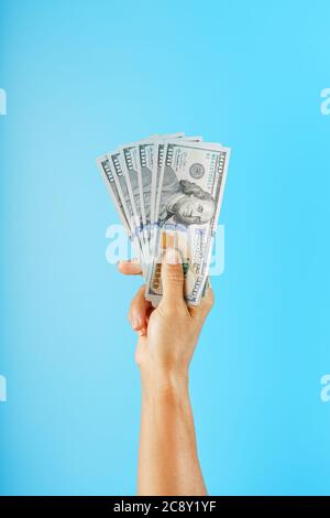 Wad of banknotes in hand on a blue background. The concept of financial assistance. Stock Photo