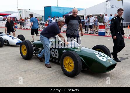 Ben Tilly's pit crew pushing his 1960, Lotus 18 373, across  the International Paddock, for the qualifying session of the Gallet Trophy For Pre '66 Grand prix Cars (HGPCA) at the 2019 Silverstone Classic Stock Photo