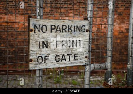 NO PARKING IN FRONT OF GATE. Old painted sign. Stock Photo