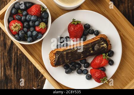 Eclair cake with chocolate glaze on wooden tray Stock Photo