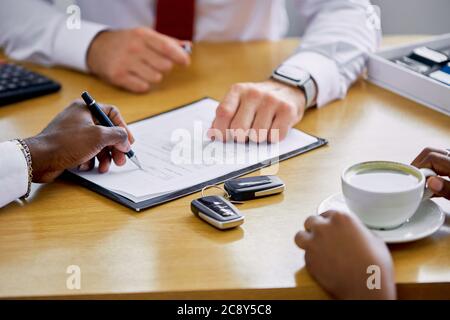 african customer signing contract at car dealership, consultant help buyers to make purchase Stock Photo