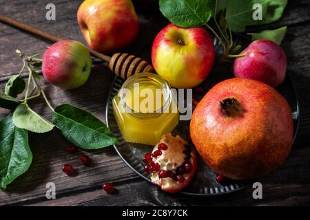 Rosh hashanah (hashana) - jewish new year holiday concept. Traditional symbols: honey, fresh apples and pomegranate on a wooden table.