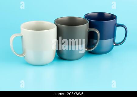 Three ceramic cups isolated on blue background. Stock Photo