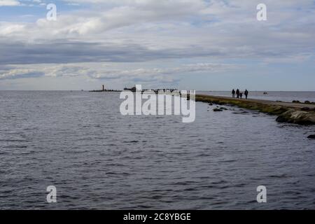 View to the Mangalsala mole crowded with fishermen catching fish in the Baltic sea Stock Photo