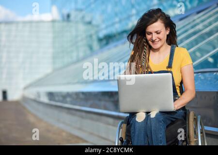 happy cute businesswoman in wheelchair working using a laptop, disability overcoming concept. blurred background, studio shot.copy space.job, professi Stock Photo