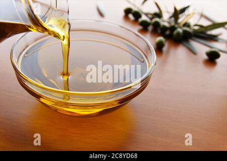 Pouring olive oil from jar to the bowl stock photo Stock Photo