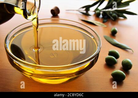 Pouring olive oil from bottle to the bowl stock photo Stock Photo