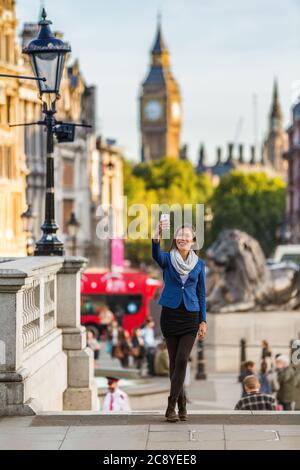 London travel tourist taking selfie picture with mobile phone near Big Ben, UK. Business people at Trafalgar Square, United Kingdom. Europe Stock Photo