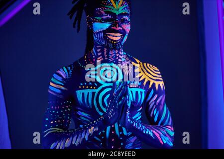 Handsome guy with UV body art close his face Stock Photo by