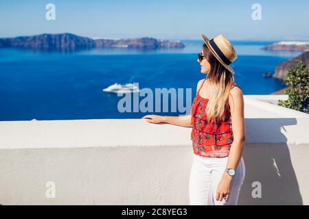 Summer vacation. Woman traveler looks at Caldera from Fira, Santorini island, Greece enjoying sea view. Tourism Stock Photo