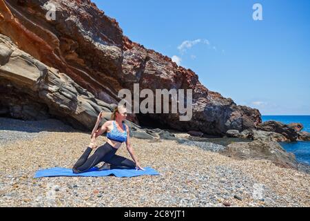 Young woman does yoga on the seashore in Greece Stock Photo
