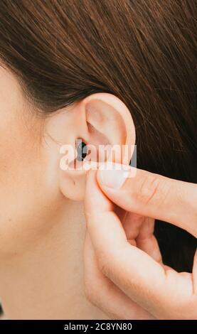 Intra-ear hearing aid close-up on female ear. The hearing solution, audiologist inserting hearing aid, close-up. Stock Photo