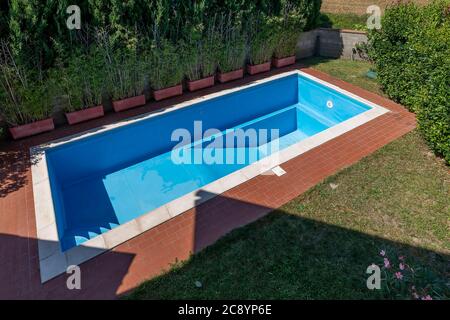 Top view of a swimming pool with blue coating in a private garden is completely empty, waiting to be filled with water for the start of the summer sea Stock Photo
