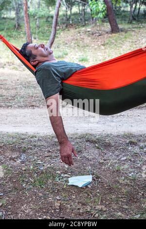 Man sleeping in a hammock with his mask off Stock Photo
