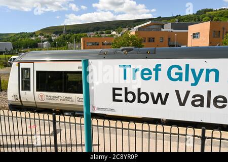 Ebbw Vale, Wales - July 2020: Board with station name at Ebbw Vale Town railway station. A train is in the background. Stock Photo