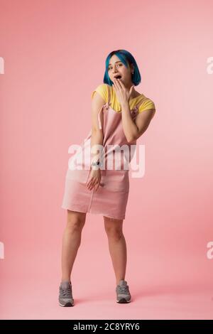 stylish scared woman closes her mouth with hand isolated over pink background. full length photo.gossip concept. word spoken is past recalling.fashion Stock Photo