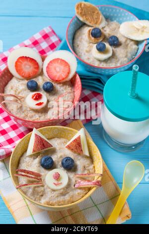 Funny bowls with oat porridge with cat, dog and mouse faces made of fruits and berries, food for kids idea Stock Photo