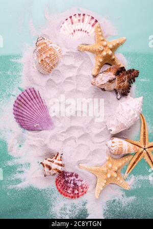Border of Starfishes and seashells on dune sand and aquamarine color background. Top view marine Vacation backdrop. Stock Photo