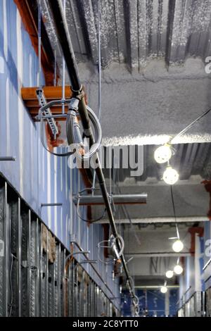 An interior corridor of a building under construction, with temporary work lights, exposed studs, fire suppression system and electrical conduits. Stock Photo