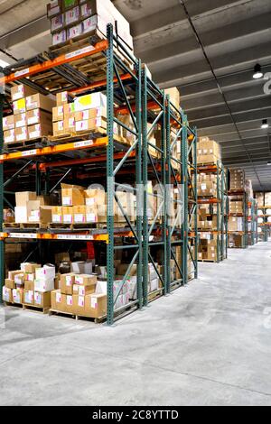 Boxes of merchandise on wood pallettes sitting on shelves in a warehouse prior to shipment. Stock Photo