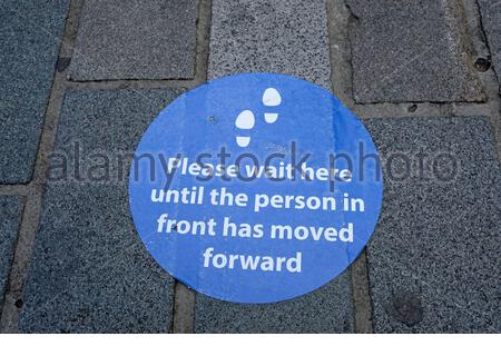 Covid-19 Coronavirus lockdown measures, social distancing reminder on pavement. Stock Photo