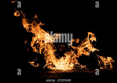 A bright, vibrant orange flame burns, the fire dancing on a black background. Stock Photo