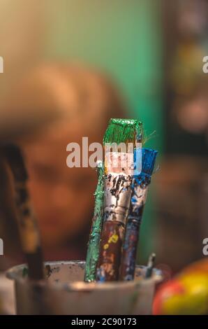 Used paintbrushes with dried paint left standing in a cup Stock Photo