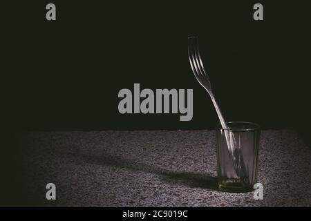 fork in a faceted glass with edgeson a black background. Studio concept photography Stock Photo